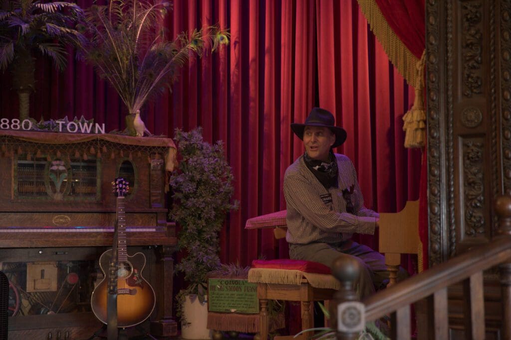 Man wearing western ware playing the piano during Buckaroo Revue live entertainment show at 1880 Town