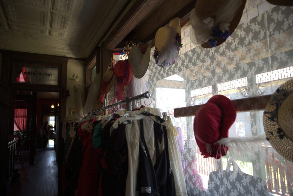 View of hats and clothing on a rack for costume rentals at 1880 Town