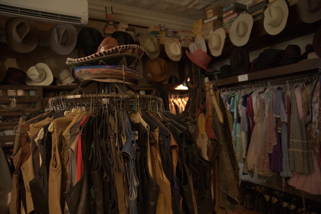 View of cowbow hats, vests and clothing on racks for costume rentals